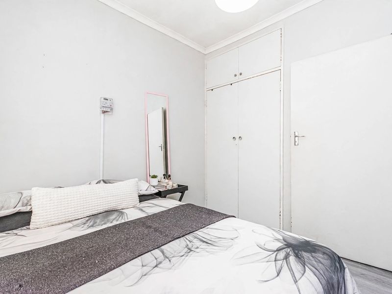 A functional bedroom featuring built-in cupboards, neutral wall finishes, and a standard internal door, providing a clean and simple living space.