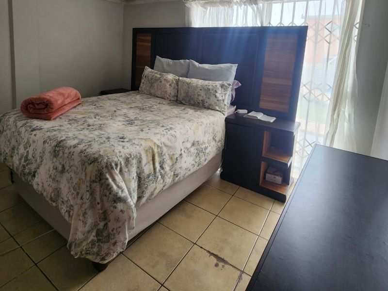 A bedroom featuring tiled flooring and a window with security bars, providing a functional space with standard finishes.