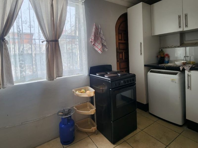 A compact kitchen featuring built-in cabinetry, a freestanding stove, and tiled flooring, offering a functional space with potential for modernization.