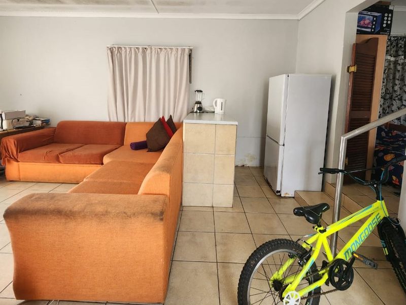 Open plan living area featuring tiled flooring and a built-in tiled breakfast counter, showing signs of wear and potential moisture damage on the lower walls.