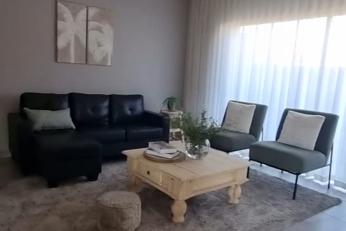 A well-maintained living room featuring neutral wall tones, large windows with curtain tracks, and durable tiled flooring.