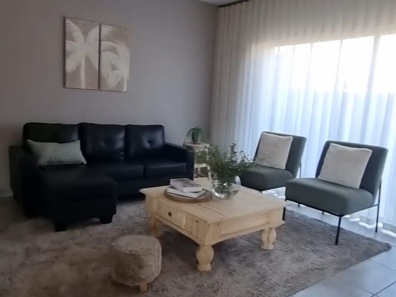 A well-maintained living room featuring neutral wall tones, large windows with curtain tracks, and durable tiled flooring.