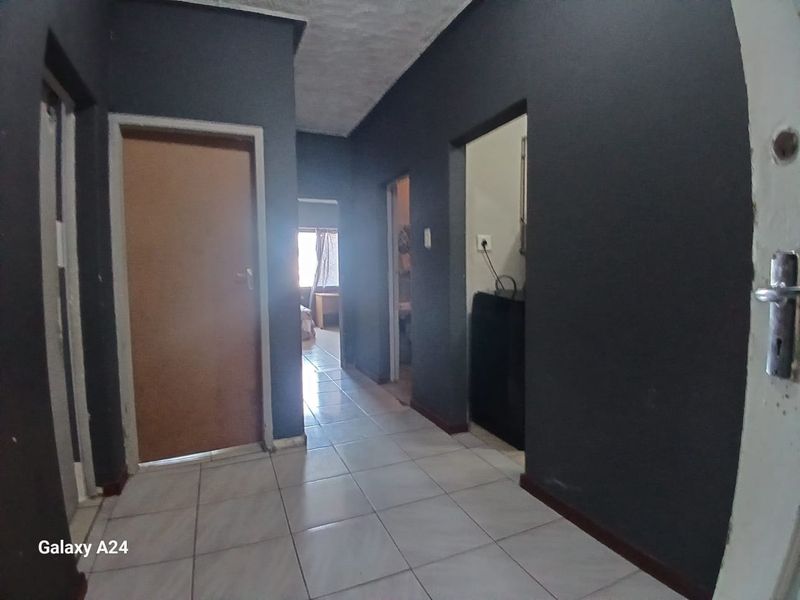 A functional hallway featuring tiled flooring and access to multiple rooms, finished with dark painted walls.