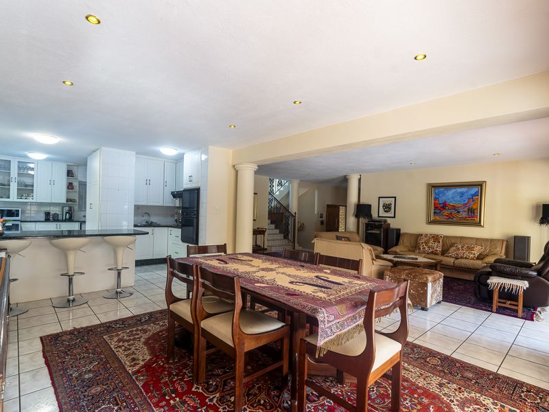 Spacious open-plan living, dining, and kitchen area featuring tiled floors, recessed lighting, and a functional kitchen layout with a breakfast bar.