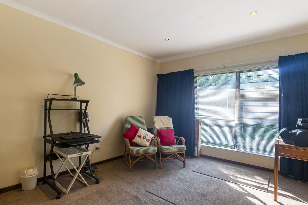 A functional bedroom featuring neutral walls, carpeted flooring, and a large window with integrated blinds, providing ample natural light.