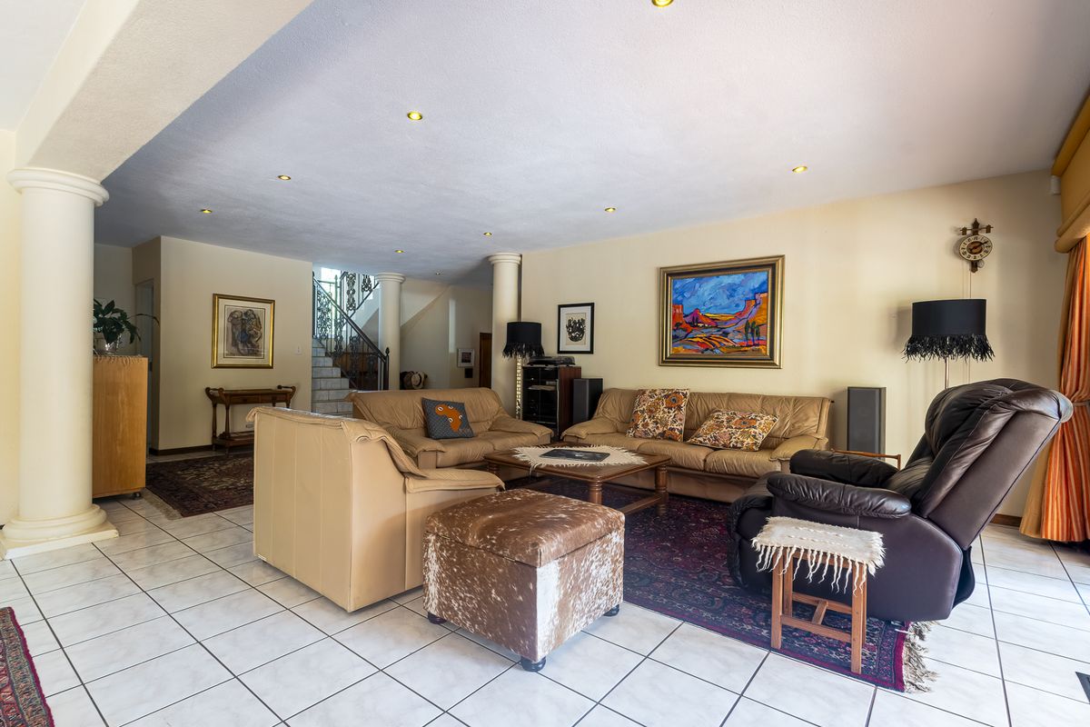 Spacious living area featuring tiled flooring, recessed lighting, and structural columns, with an open view toward the staircase.