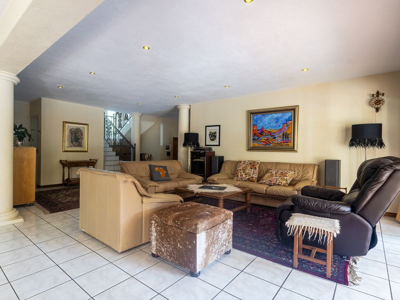 Spacious living area featuring tiled flooring, recessed lighting, and structural columns, with an open view toward the staircase.