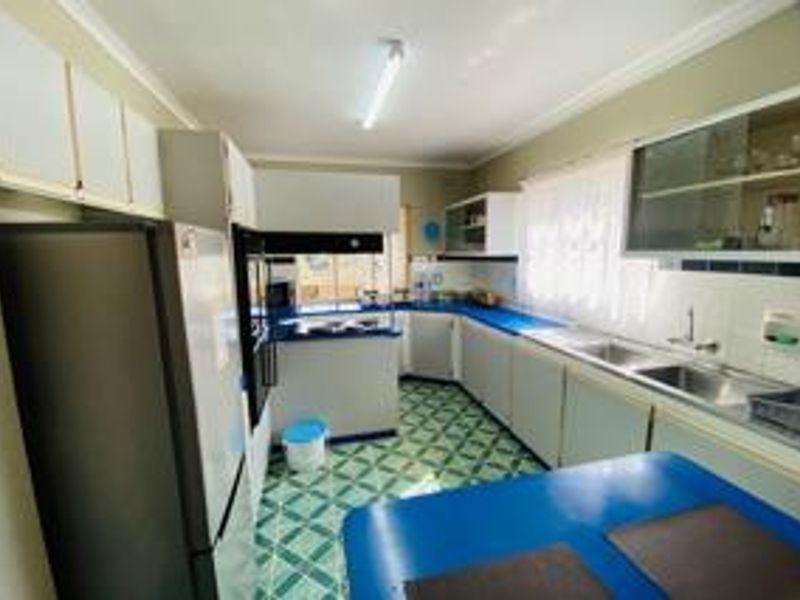 A functional kitchen featuring extensive built-in cabinetry, a double basin sink, and a built-in oven, with traditional tiled flooring and countertops.