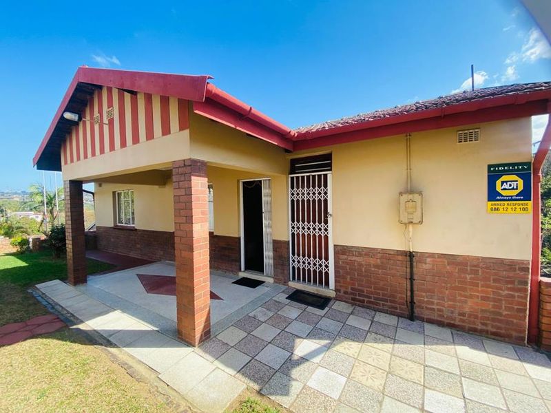 Front entrance area featuring a covered patio with brick pillars, tiled flooring, and a secure entrance gate.