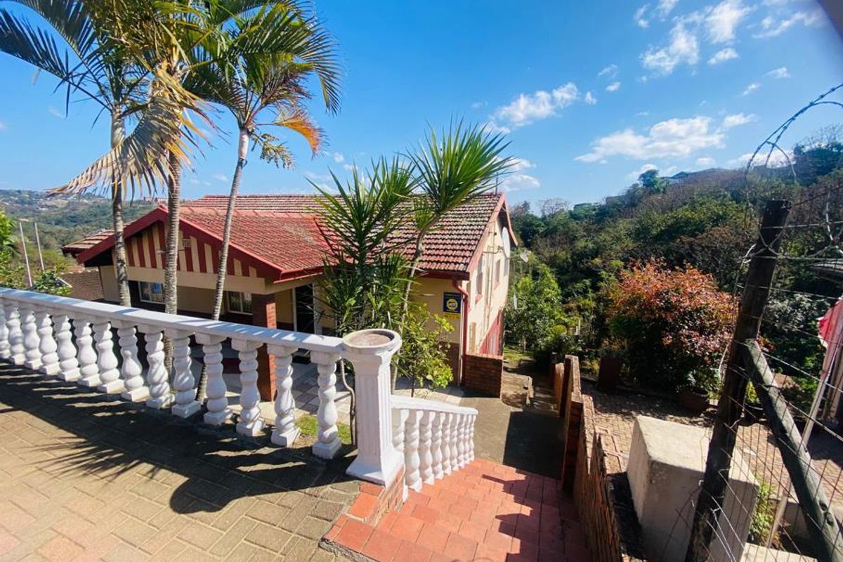 Rear exterior view of the house featuring a paved patio area, balustrade, and brick staircase leading to the garden.