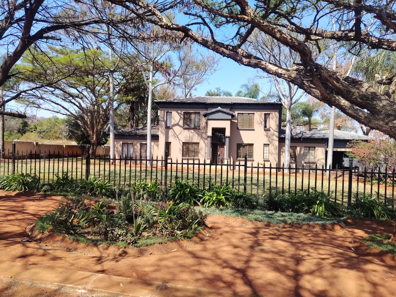 A well-maintained two-story residential property featuring a neutral facade, tiled roof, and a secure front garden with wrought iron fencing.
