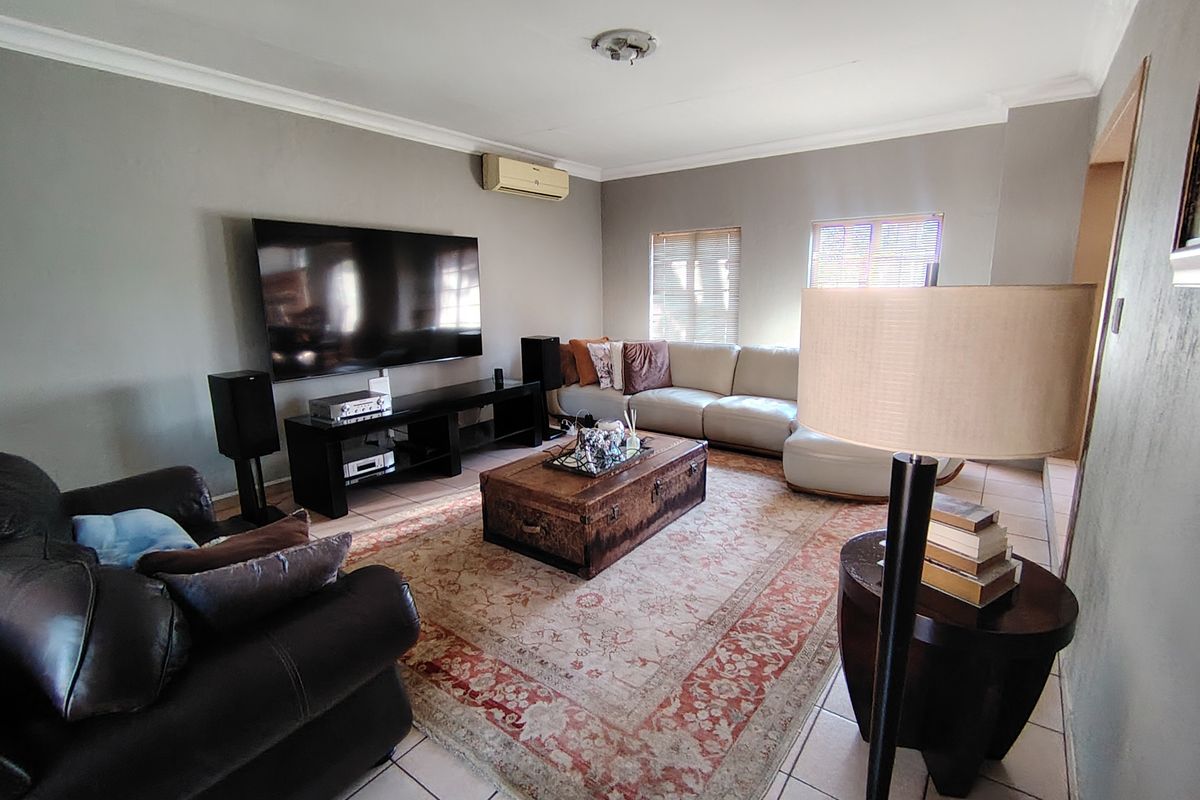 A comfortable living room featuring tiled flooring, cove cornicing, and a wall-mounted split-system air conditioner.