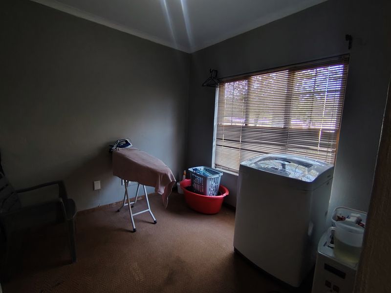A functional laundry room featuring a window with venetian blinds, providing a dedicated space for washing and utility tasks.