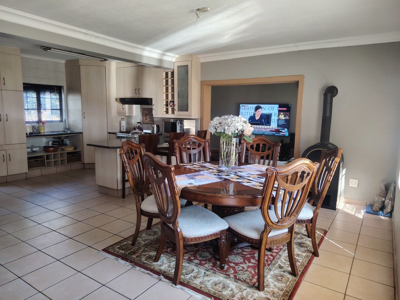Open-plan living and dining area featuring tiled floors, a functional kitchen with built-in cabinetry, and a cozy freestanding fireplace.