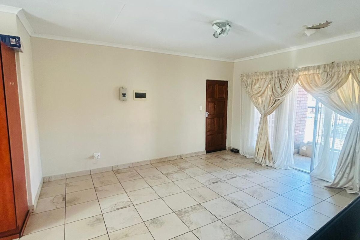 An empty living room featuring tiled flooring, a sliding glass door leading to an outdoor area, and a ceiling light fixture.