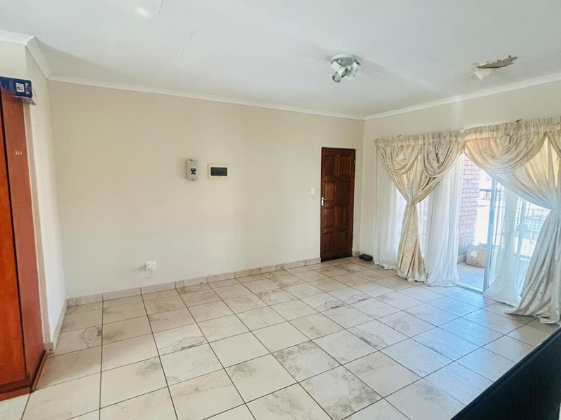 An empty living room featuring tiled flooring, a sliding glass door leading to an outdoor area, and a ceiling light fixture.