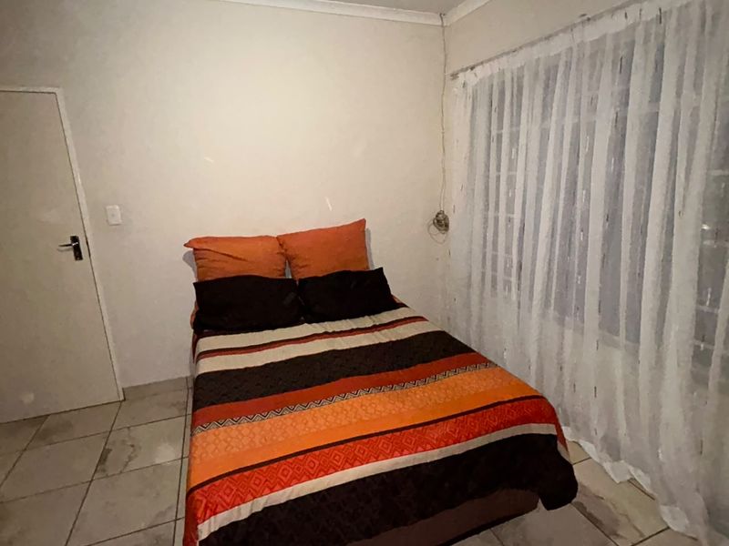 A bedroom featuring tiled flooring and cove cornice detailing, requiring cosmetic updates to improve the overall finish and appeal.