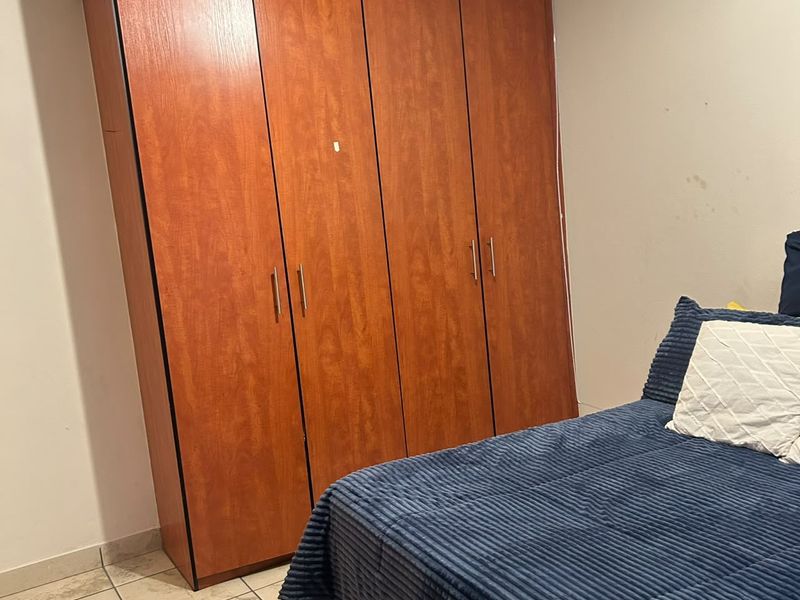 Bedroom featuring tiled flooring and a large, full-height built-in wooden wardrobe.