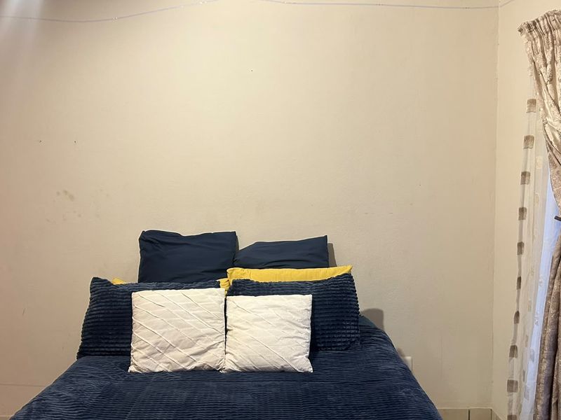 A bedroom featuring tiled flooring and cove cornicing, currently showing signs of wear on the wall surfaces.