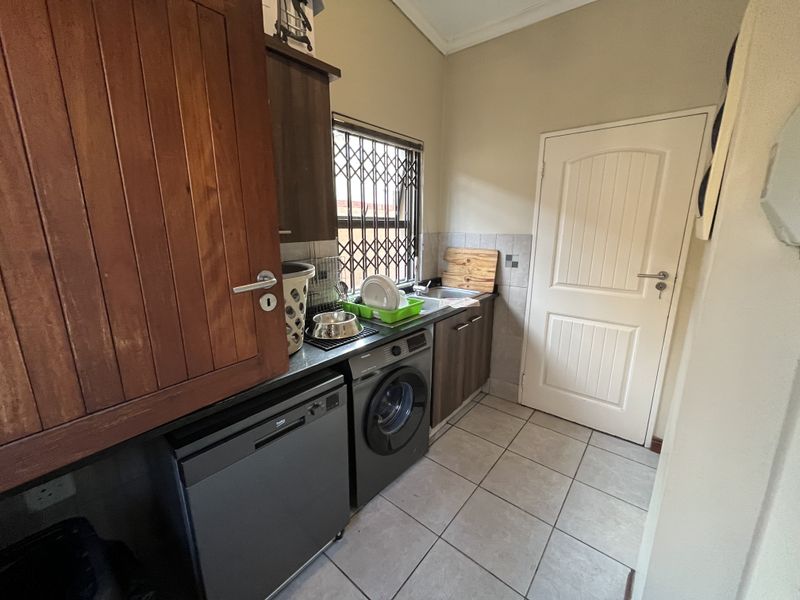 Functional laundry room featuring built-in cabinetry, tiled flooring, and dedicated plumbing connections for appliances.