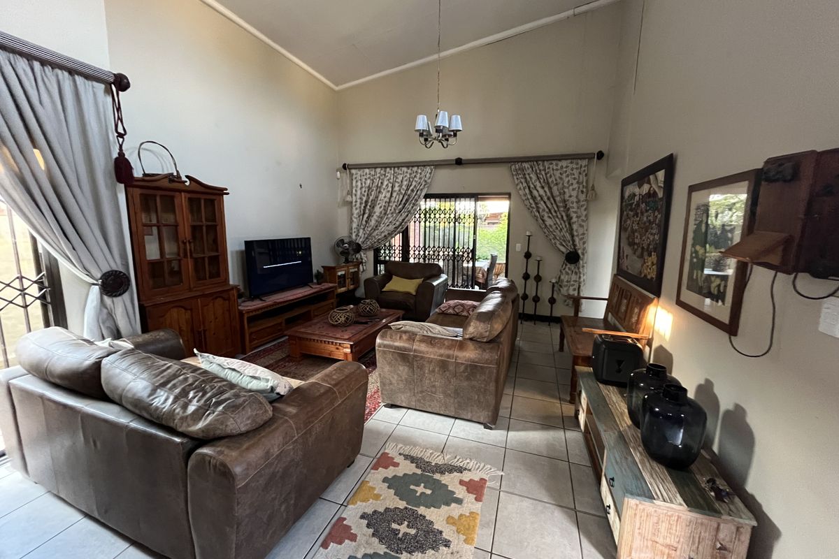 Spacious living room featuring high vaulted ceilings, tiled flooring, and large sliding glass doors providing access to the outdoor area.