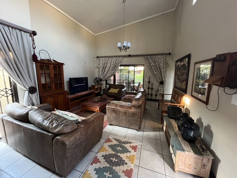 Spacious living room featuring high vaulted ceilings, tiled flooring, and large sliding glass doors providing access to the outdoor area.