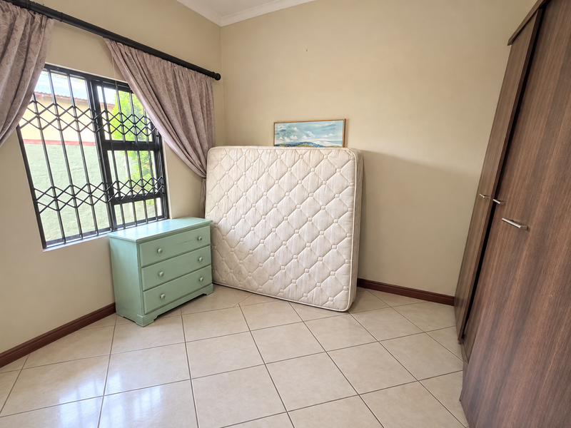 A bedroom featuring tiled flooring, a built-in wardrobe, and a window fitted with a security gate.