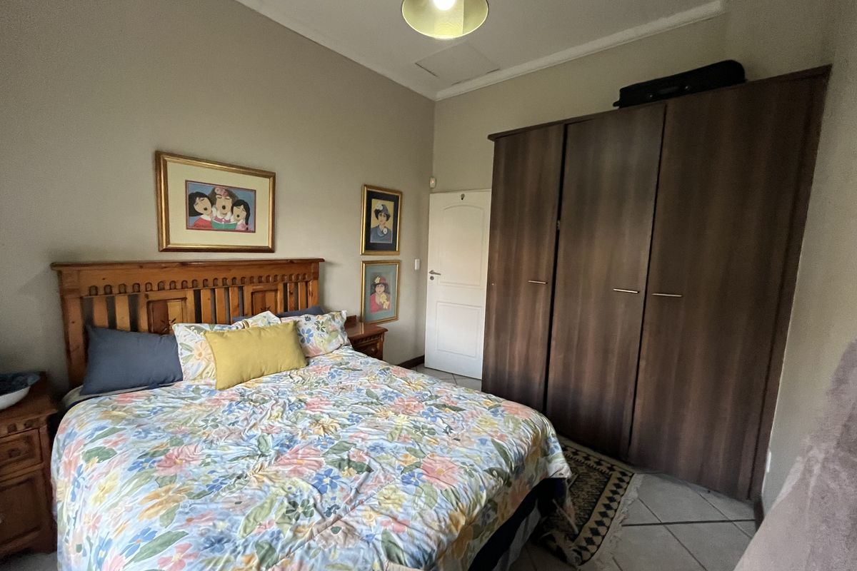 A bedroom featuring tiled flooring, a built-in wooden wardrobe, and a ceiling light fixture.
