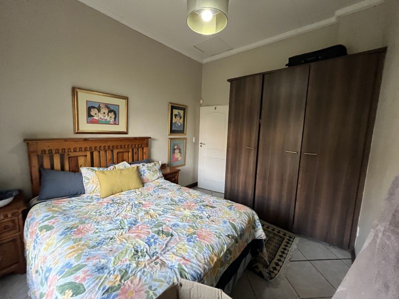 A bedroom featuring tiled flooring, a built-in wooden wardrobe, and a ceiling light fixture.