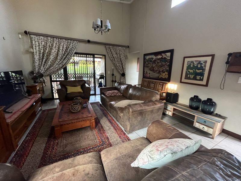 Spacious living room featuring high vaulted ceilings, tiled flooring, and a sliding glass door providing access to the outdoor patio area.