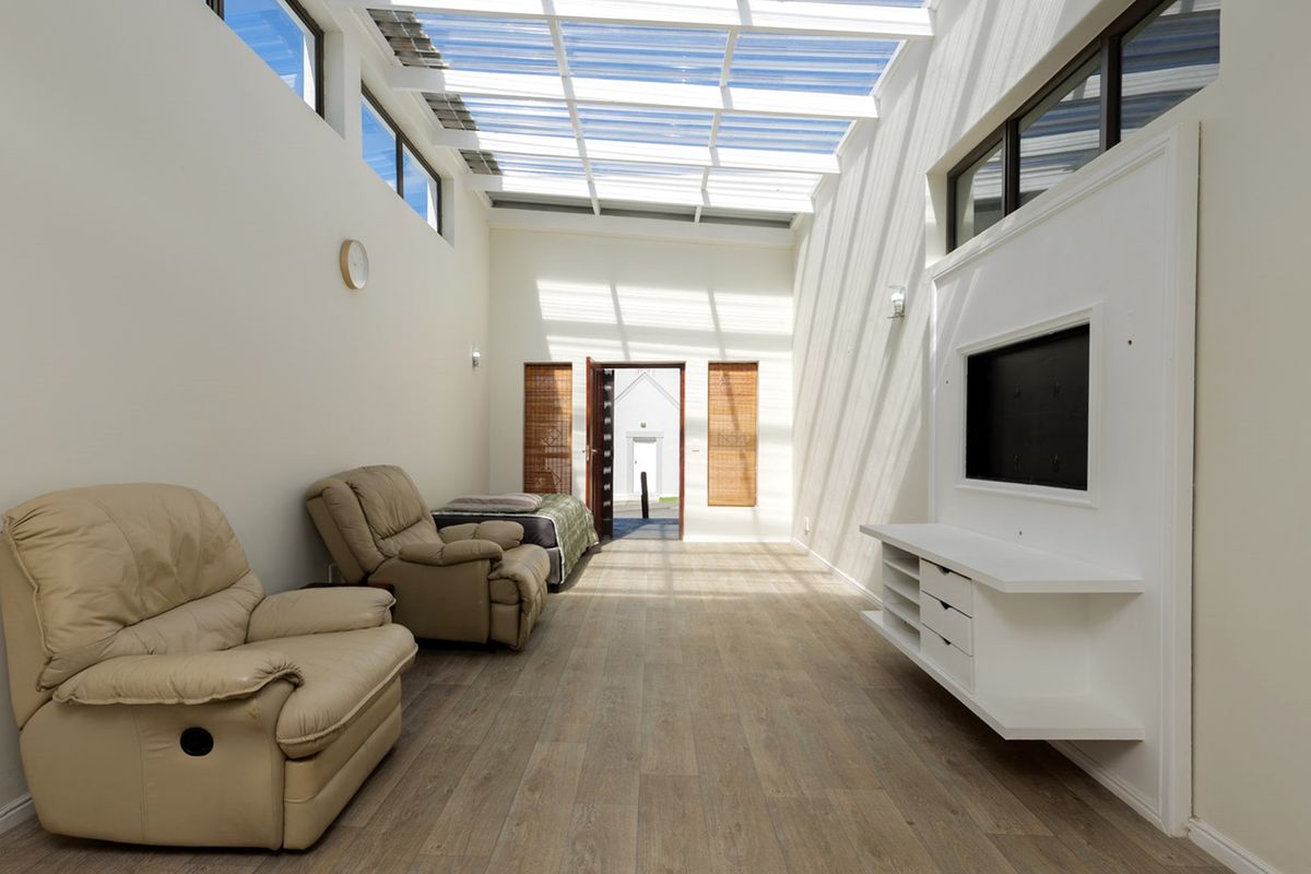 Bright and airy living room featuring a large skylight, clerestory windows, modern laminate flooring, and a built-in media console.