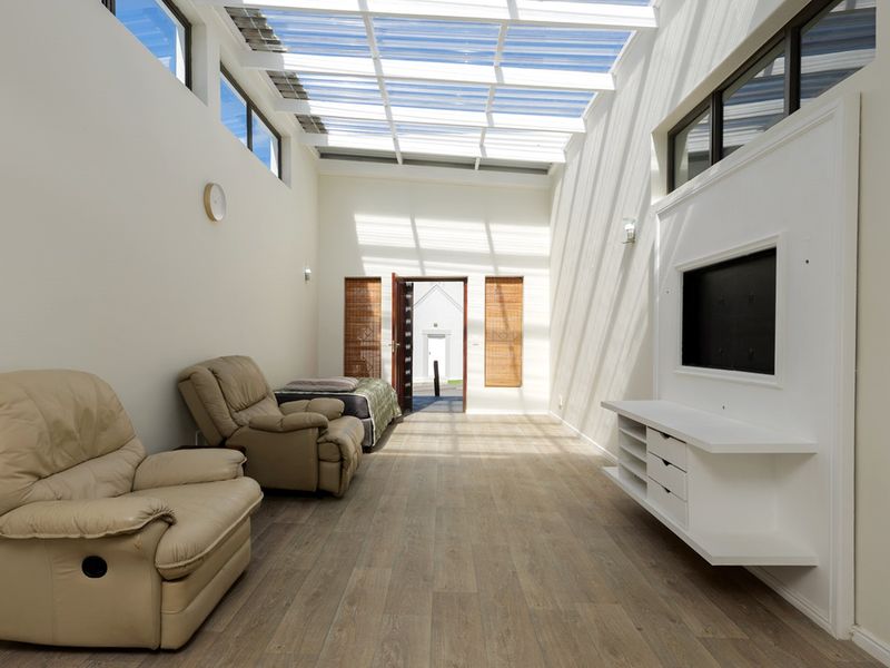 Bright and airy living room featuring a large skylight, clerestory windows, modern laminate flooring, and a built-in media console.