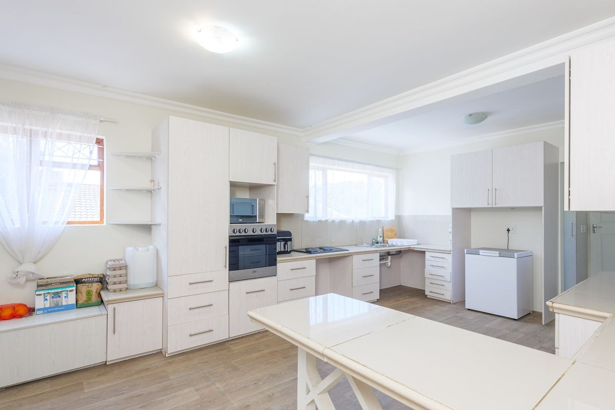 A functional kitchen featuring light-toned laminate cabinetry, built-in oven and microwave, ample counter space, and durable laminate flooring.