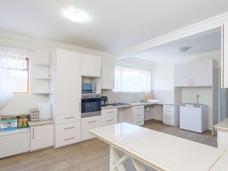 A functional kitchen featuring light-toned laminate cabinetry, built-in oven and microwave, ample counter space, and durable laminate flooring.