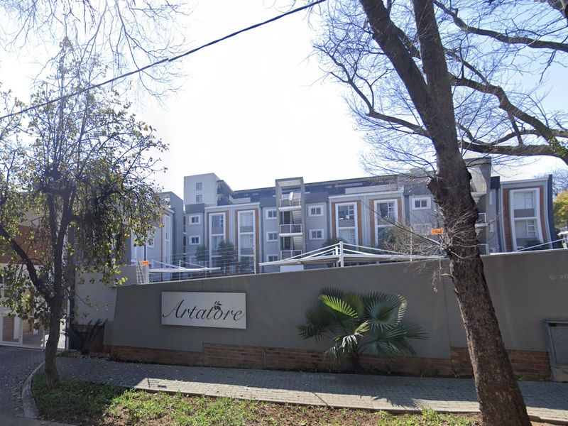 Street view of the Artatore apartment complex, featuring a modern multi-story facade, perimeter wall, and established landscaping.