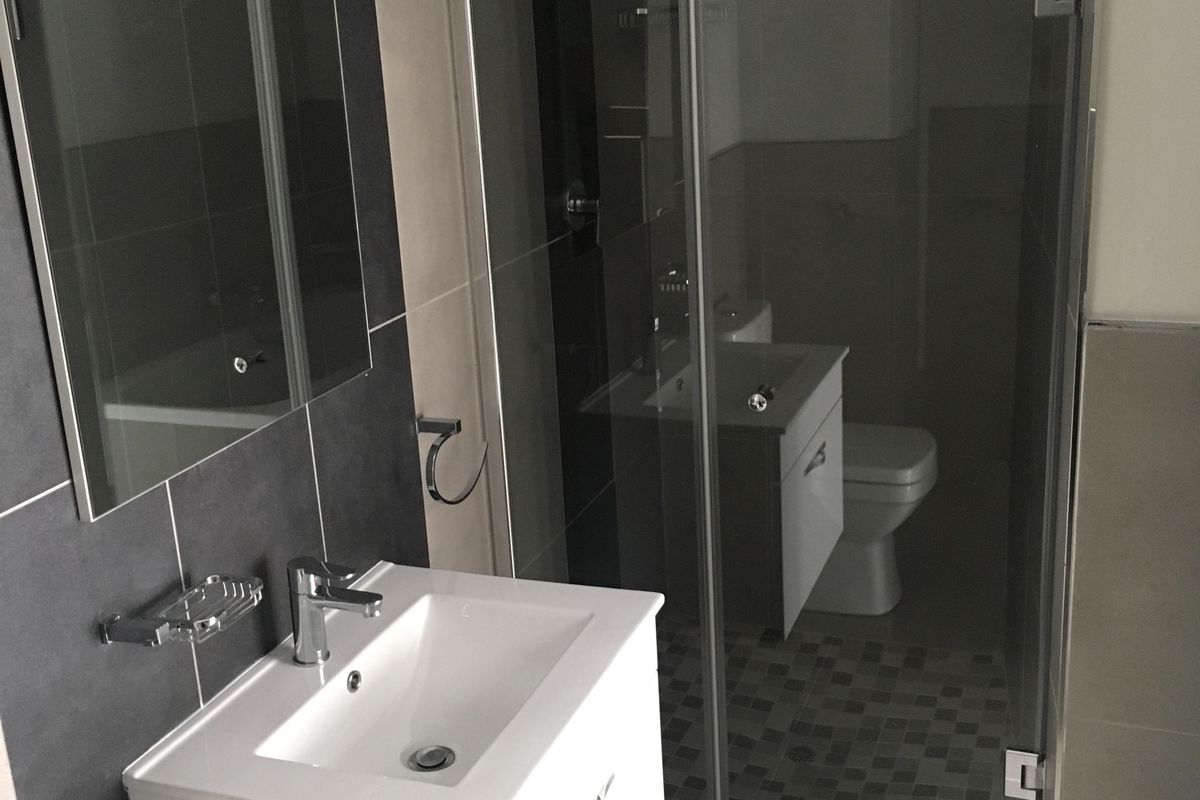 Modern bathroom featuring a wall-mounted vanity, glass-enclosed shower, and contemporary tiled finishes throughout.
