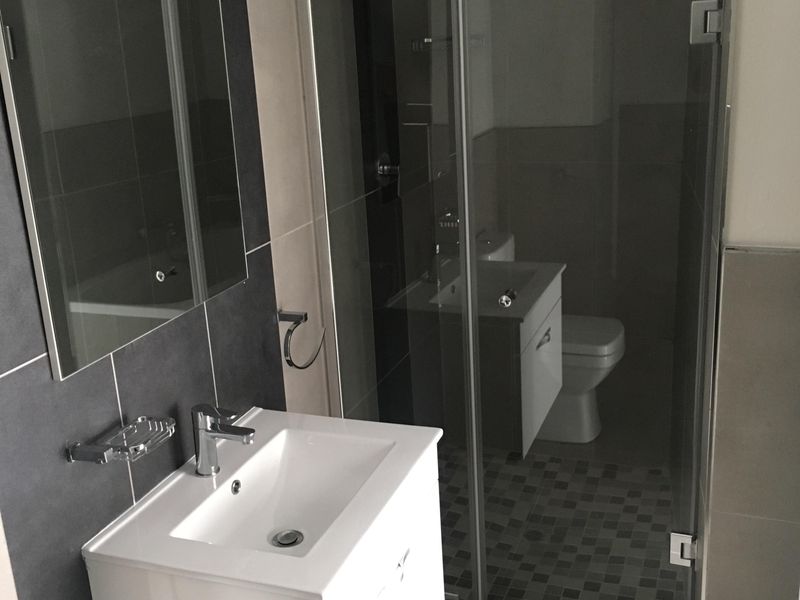 Modern bathroom featuring a wall-mounted vanity, glass-enclosed shower, and contemporary tiled finishes throughout.