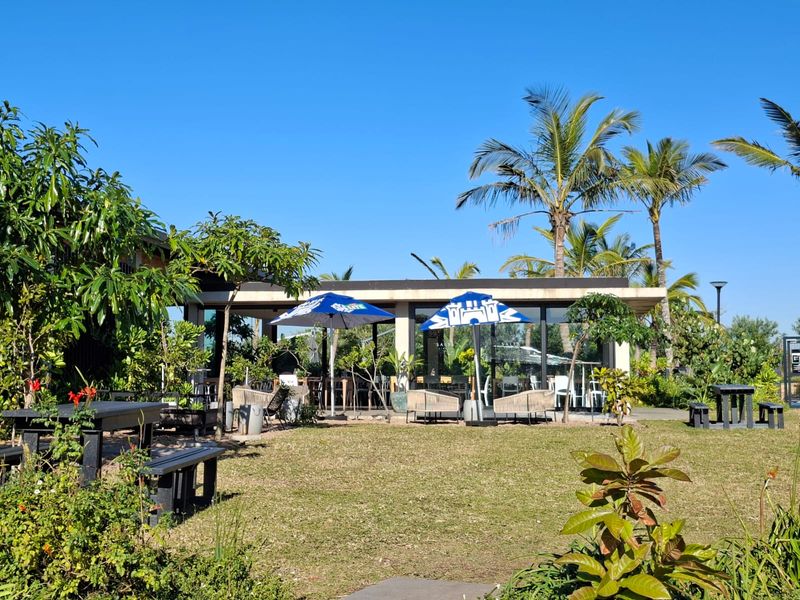 A well-maintained outdoor patio area featuring a covered structure, paved flooring, and access to a landscaped garden setting.