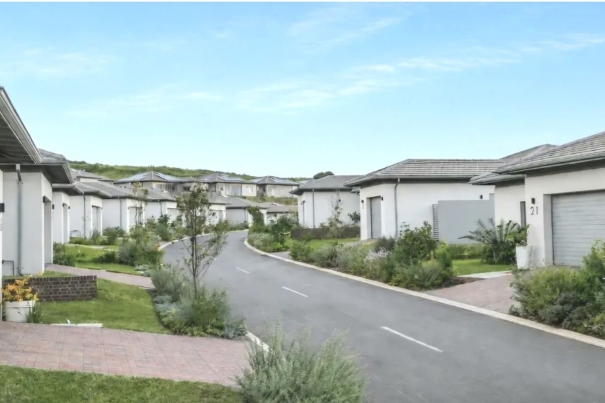 A view of a residential street within a modern estate, featuring well-maintained homes with paved driveways and landscaped gardens.