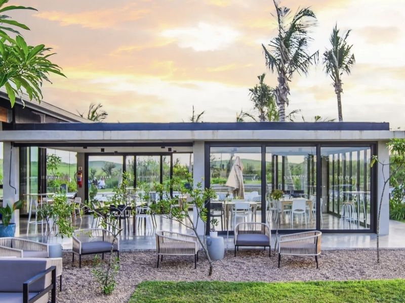 A modern covered patio area featuring expansive sliding glass doors, concrete flooring, and recessed lighting, seamlessly connecting the indoor and outdoor living spaces.
