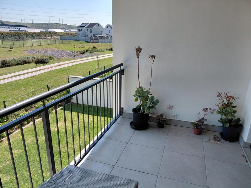A clean, tiled balcony featuring a modern metal balustrade and open views over the surrounding neighborhood.