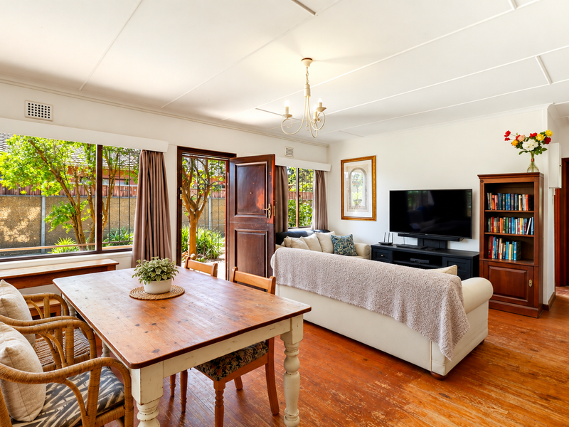 Open plan living and dining area featuring timber flooring, large windows providing natural light, and direct access to the outdoor space.