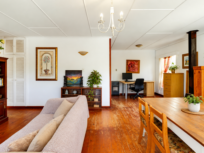 Spacious open-plan living and dining area featuring original hardwood flooring, a built-in fireplace, and integrated storage cupboards.
