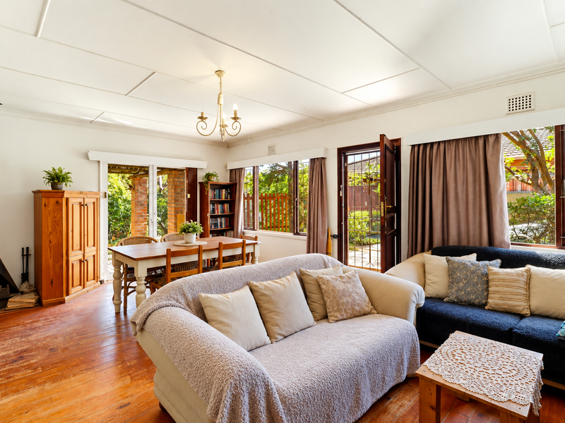 Spacious open-plan living and dining area featuring hardwood flooring, a freestanding fireplace, and direct access to the garden through sliding glass doors.