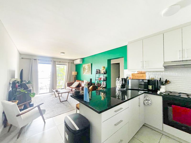 Open-plan living area featuring a modern kitchen with granite countertops, subway tile backsplash, and direct access to a private balcony.