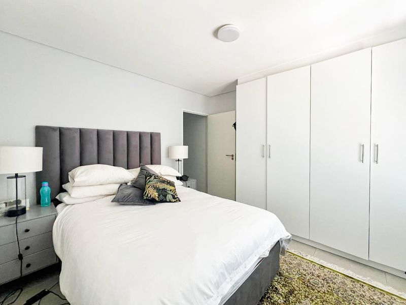 A well-maintained bedroom featuring ample built-in cupboard storage and neutral finishes, providing a clean and functional living space.