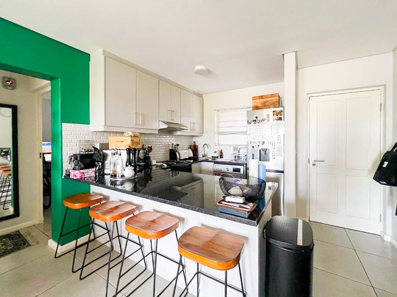 A functional kitchen featuring granite countertops, subway tile backsplash, and ample built-in cabinetry, with a breakfast bar area and tiled flooring.