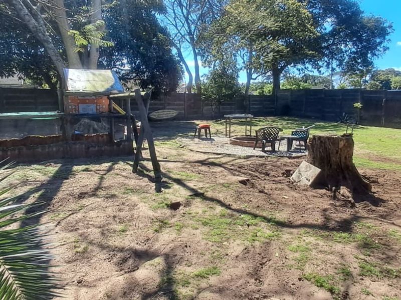 Spacious rear garden featuring perimeter fencing, a covered outdoor area, and significant landscaping potential to improve the lawn and ground surface.