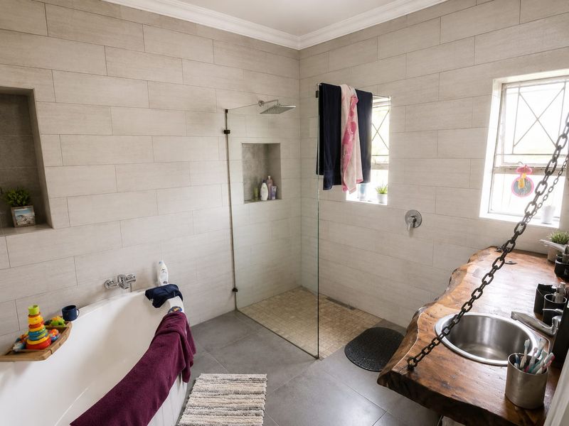 Modern bathroom featuring a walk-in shower with glass screen, a freestanding bathtub, and a unique live-edge wood vanity with an undermount sink.