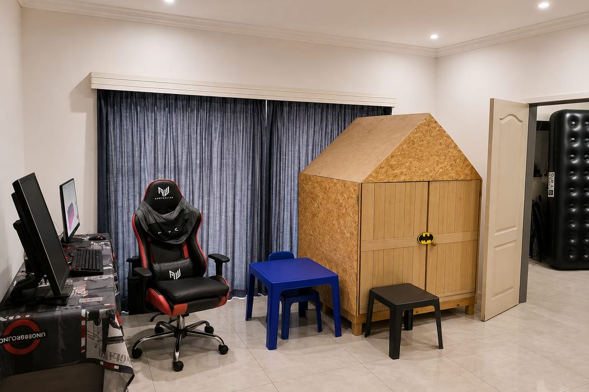 A bedroom featuring tiled flooring, recessed downlights, and a large window with curtain track, currently utilized as a multi-purpose play and study area.